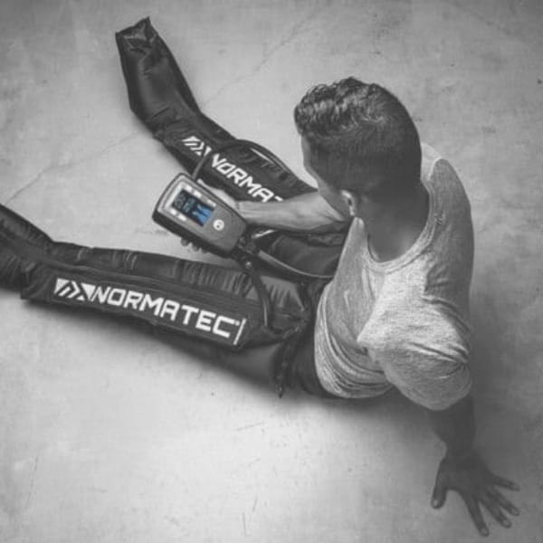 Client relaxing with compression boots in a Zivel recovery lounge